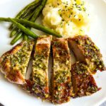 close up of garlic and herb pork tenderloin served with mashed potatoes and green beans