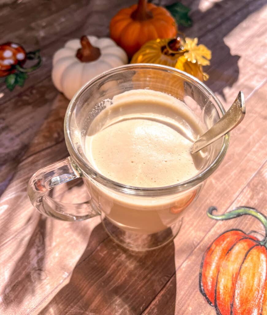 whipped pumpkin spiced latte close up shot, pumpkin decor in the background