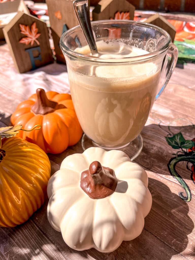dalgona pumpkin spiced latte close up shot, pumpkin decor in the background