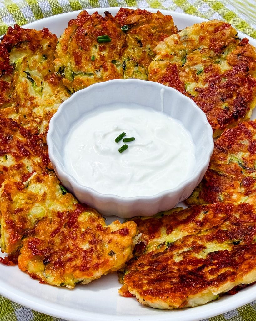 cheesy zucchini fritters view from the side served with sour cream
