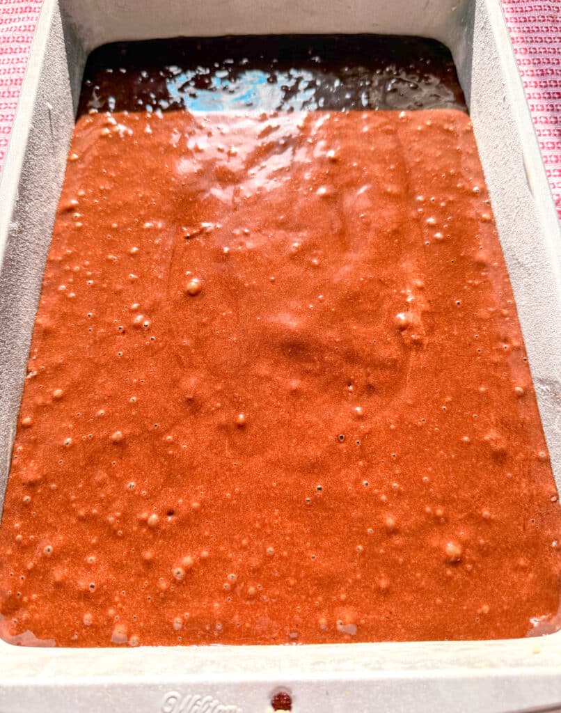 a sheet pan with bubbly chocolate cake batter ready to be baked