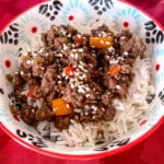 asian inspired ground beef bowl on top of white rice garnished with sesame seeds