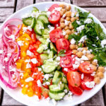 Greek Salad with pickled onions, sweet bell peppers, cucumbers, tomatoes, chickpeas, parsley, and chickpeas