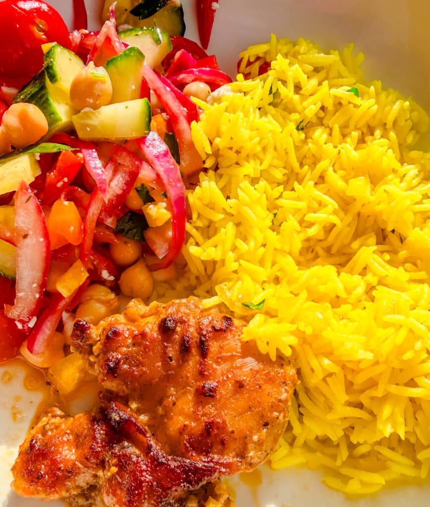 Light and fluffy yellow rice served with chicken tighs and salad