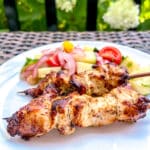 greek chicken souvlaki skewers kabobs with salad in the bakground
