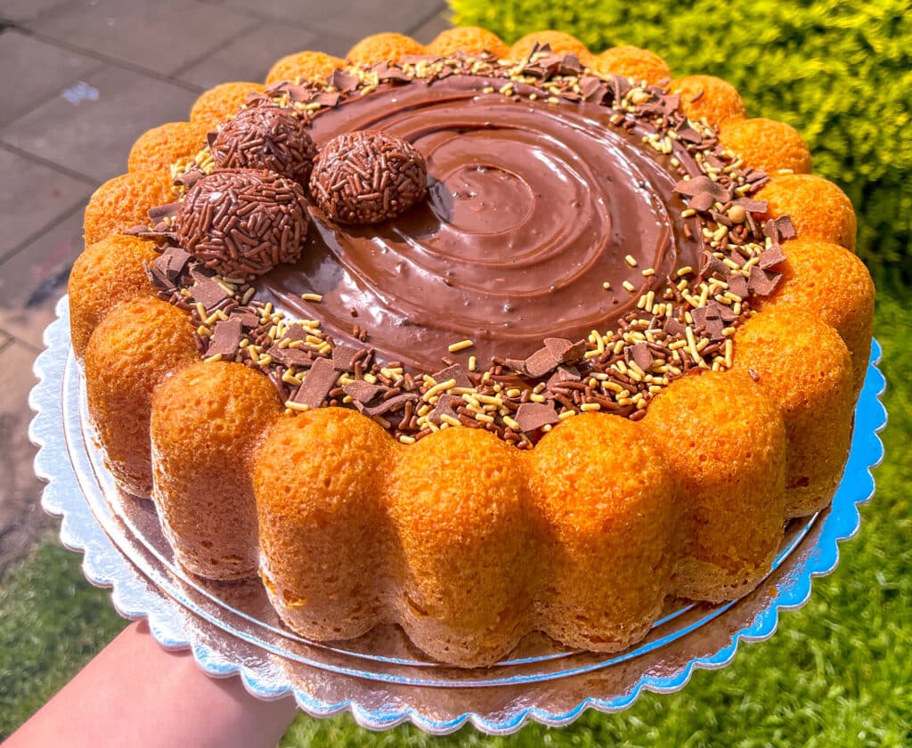 carrot cake with brigadeiro frosting and brigadeiros on top with sprinkles.