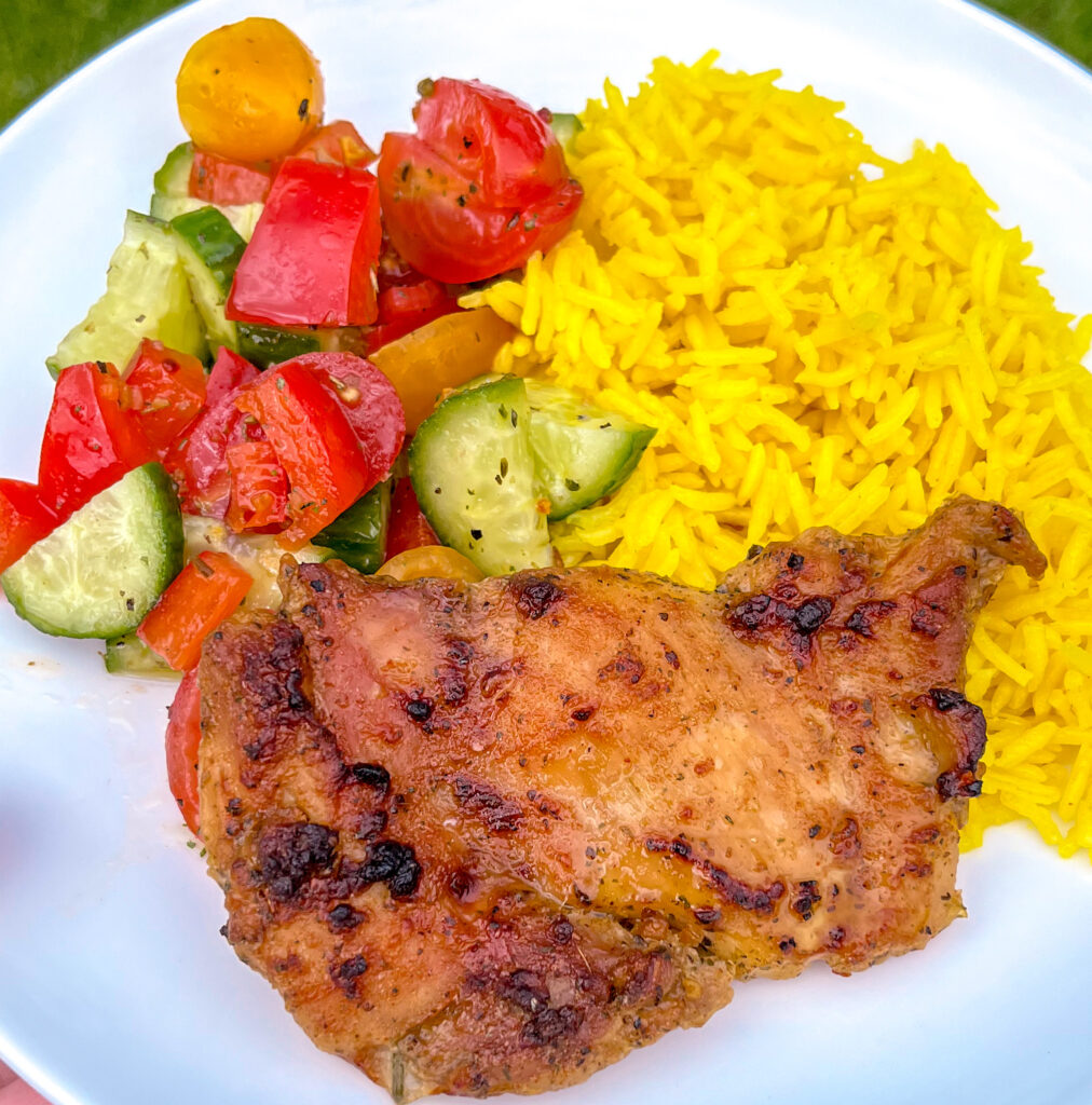 yogurt chicken served alongside yellow rice and salad