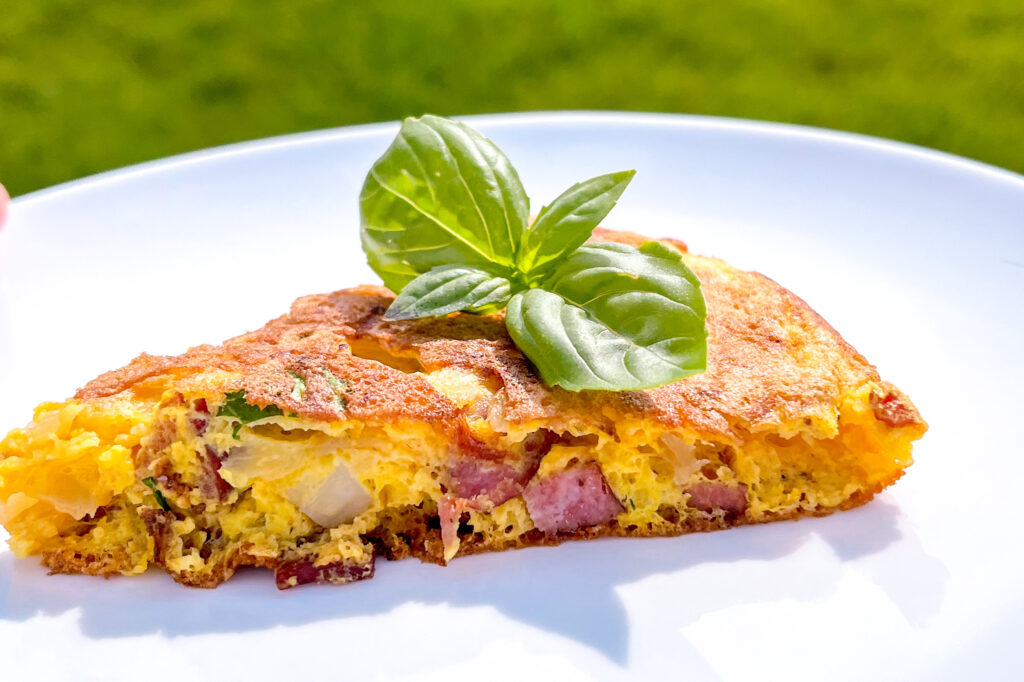 fritatta with basil on top on a white plate
