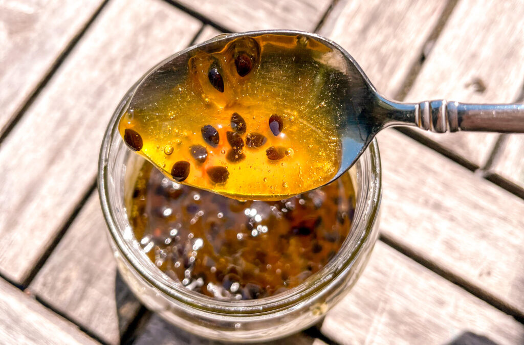 Up-close shot of a spoonful of passion fruit jam with wooden slats in the background.