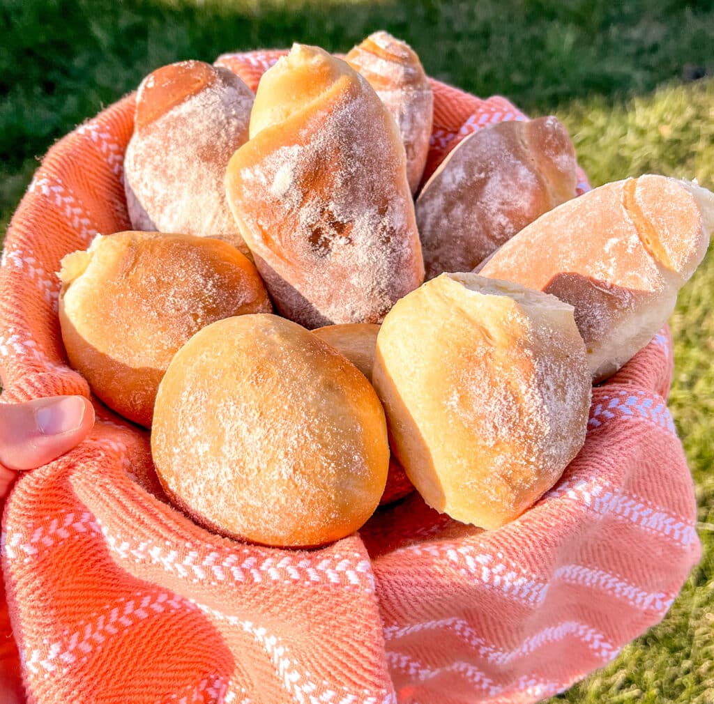 corn bread rolls in an orange basket near the grass, pao de milho
