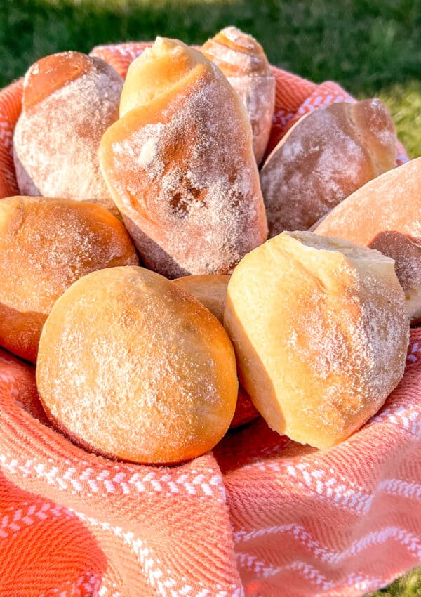 corn bread rolls in an orange basket near the grass, pao de milho