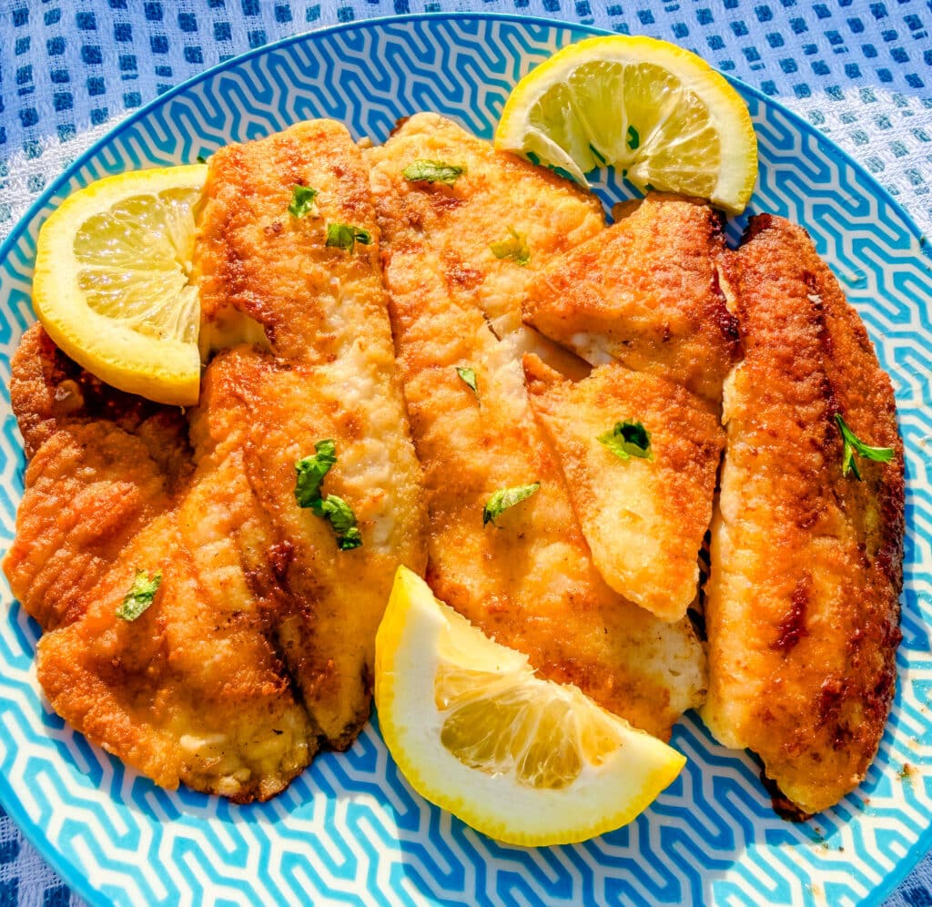 best pan fried tilapia on blue plate with lemons
