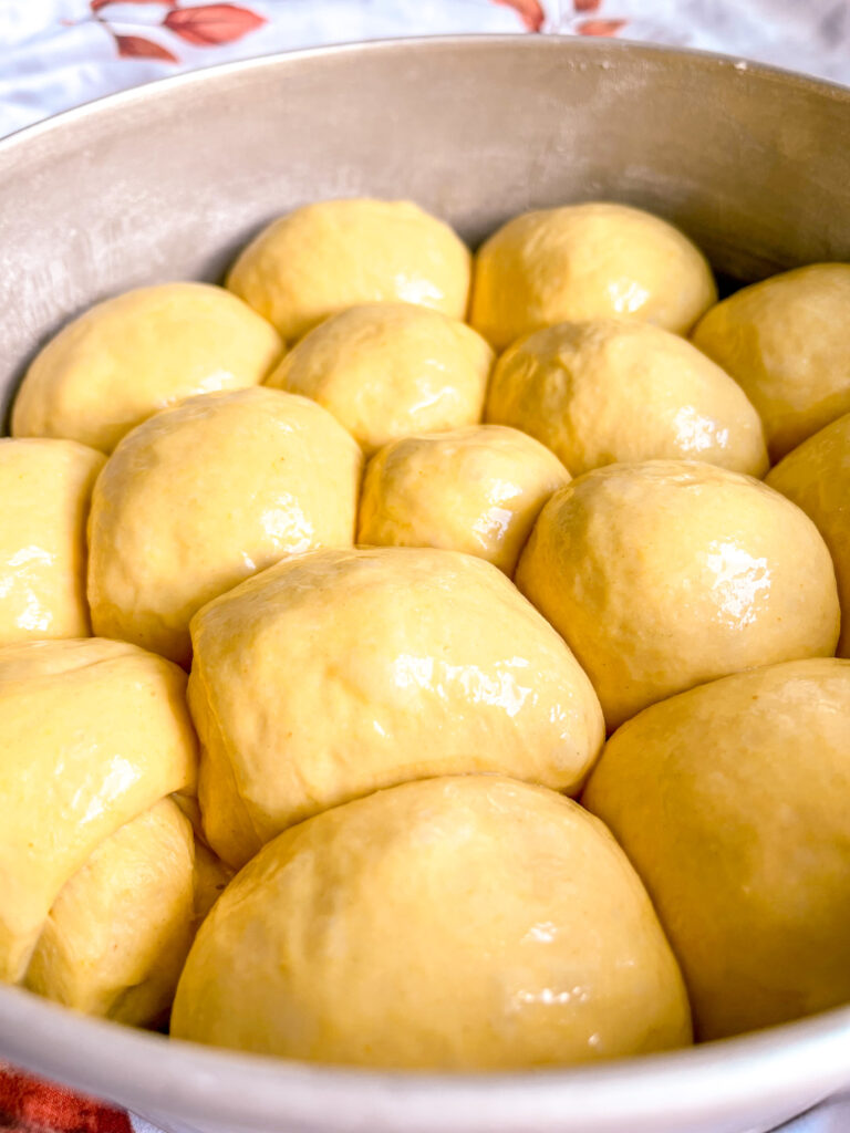 Pumpkin dinner rolls dough after rising ready to be baked in a round pan