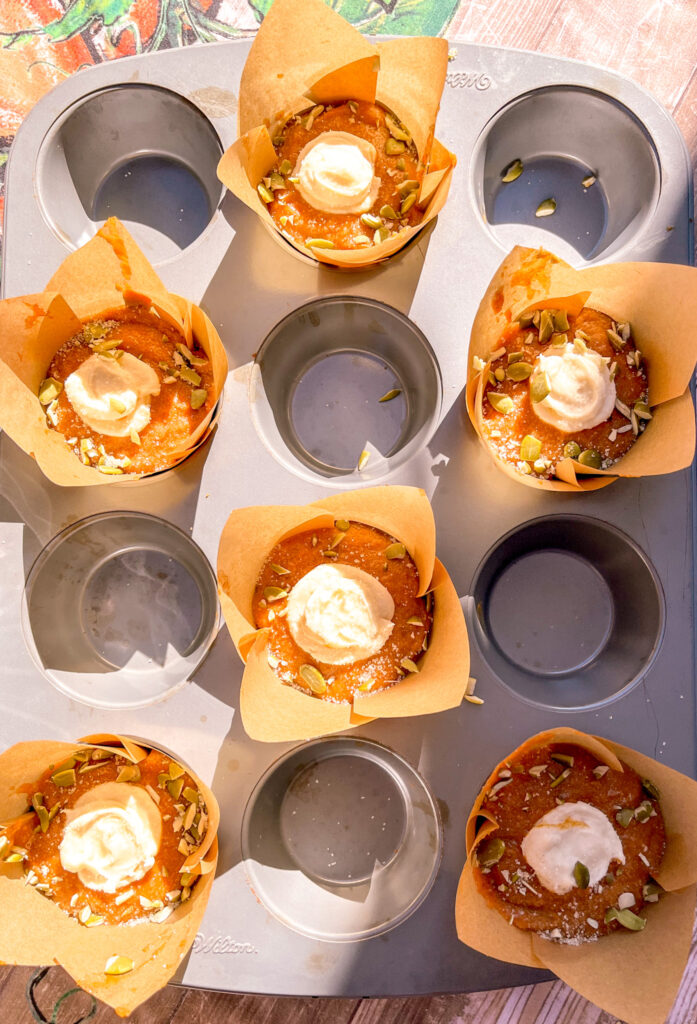 pumpkin muffin with cream cheese in muffin pan ready to be baked with seeds sprinkled on top