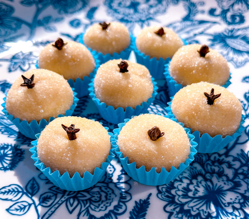white brigadeiros in blue paper cups on a blue and white plate