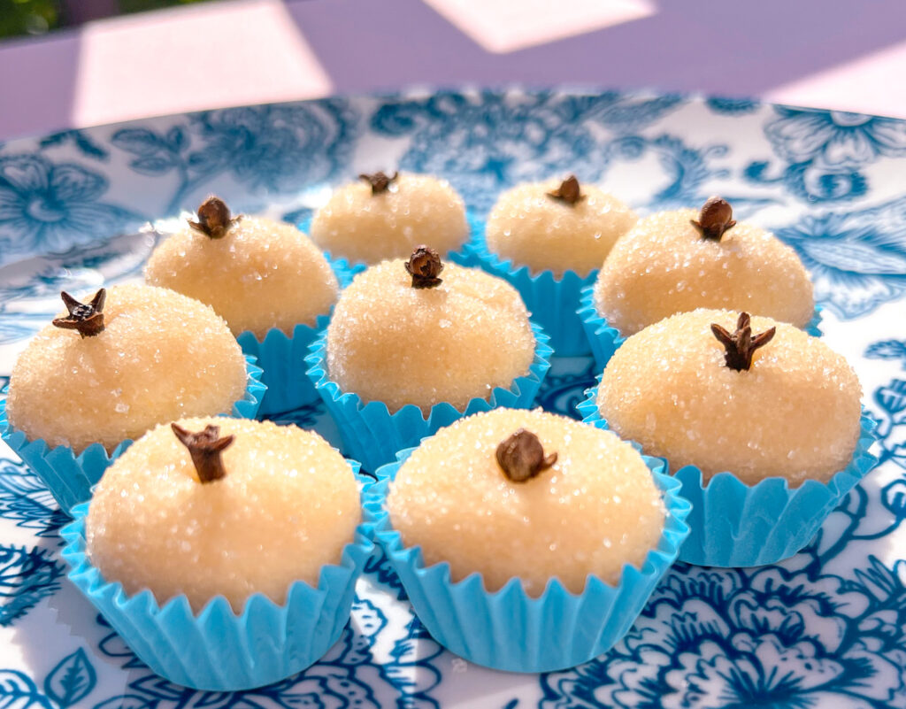 white brigadeiros in blue paper cups on a blue and white plate side view