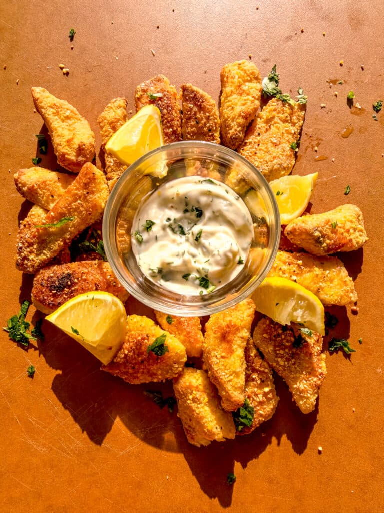 crispy tilapia decorated with lemons and parsley on a chopping board