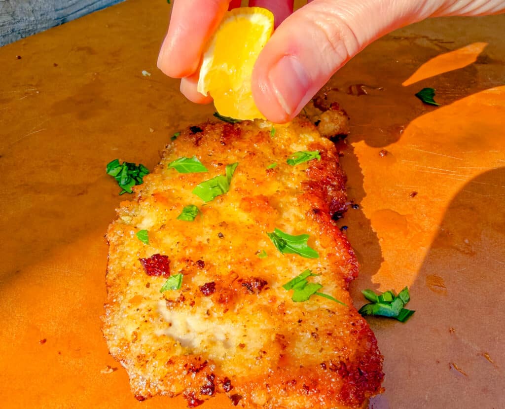 squeezing lemon on a pork chop on a cutting board