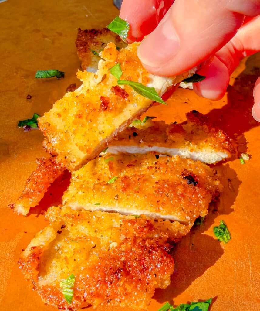 sliced parmesan pork chop on a cutting board
