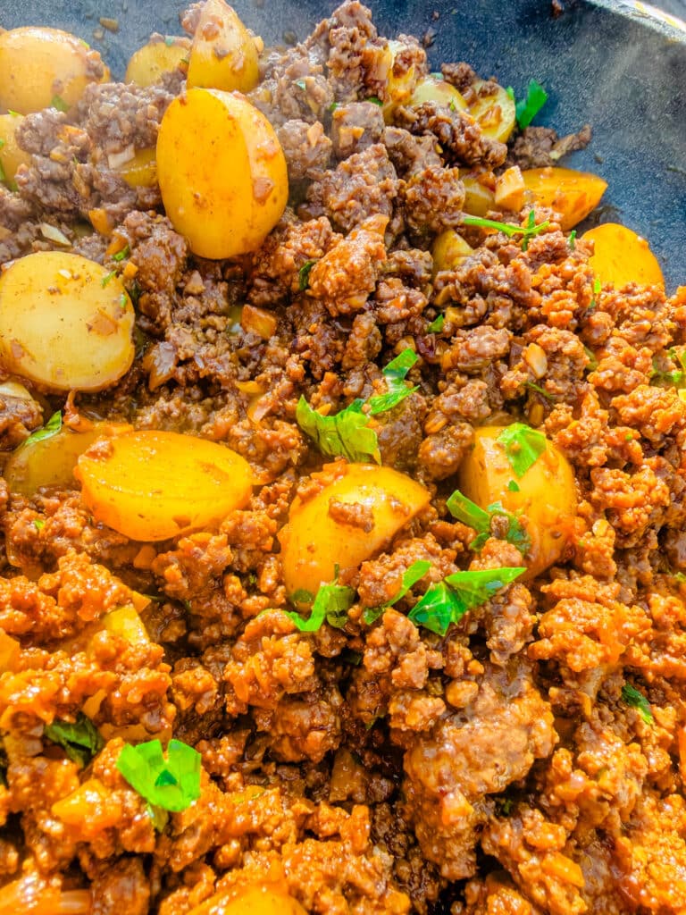 ground beef and potatoes  with steam coming out on a skillet