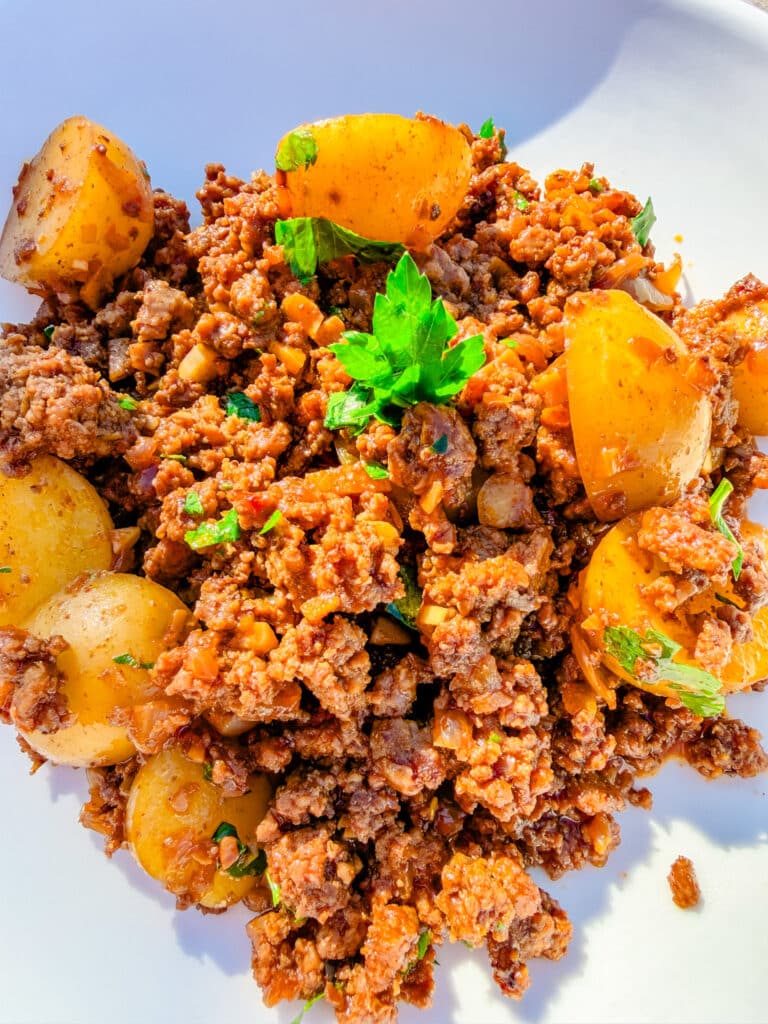 ground beef and potatoes served on a white plate