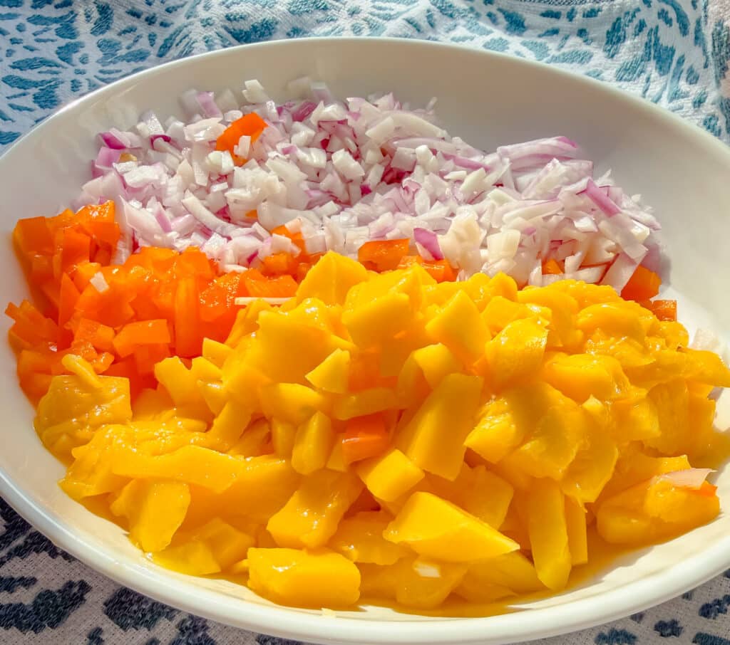 Diced mango, onion and peppers in a bowl before mixing