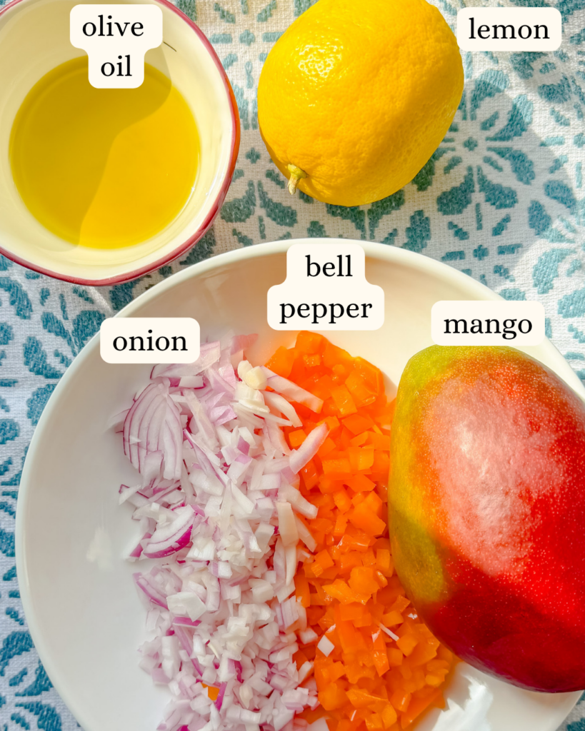 Ingredients for fresh mango salsa including mango, red onion, peppers, lemon and olive oil