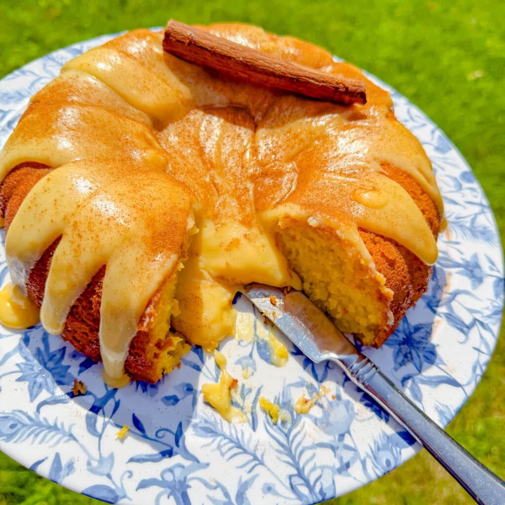 sliced Moist Brazilian corn cake with creamy corn topping and cinnamon served on a blue floral platter.